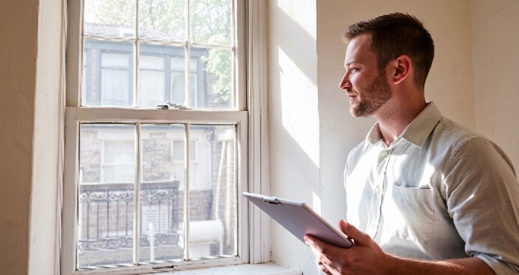 Domestic energy assessor inspecting a sash window during a home visit